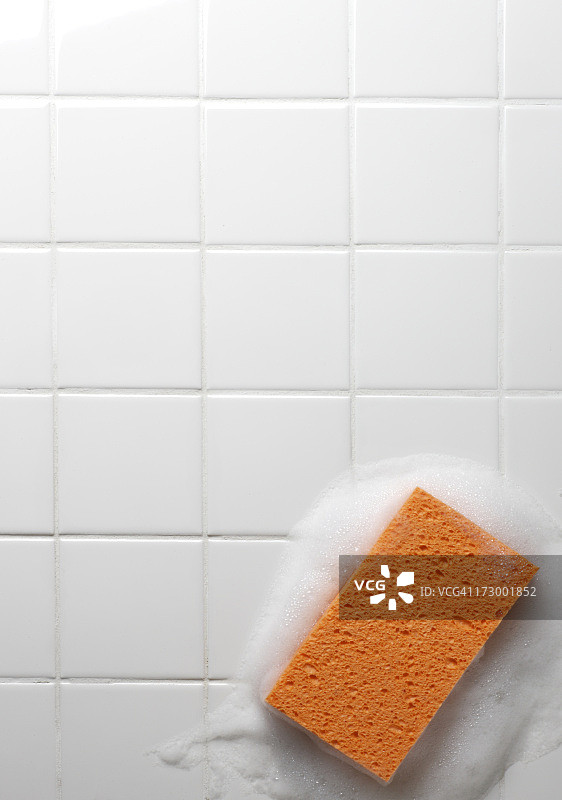 白色浴室瓷砖上沾着橙色肥皂海绵图片素材