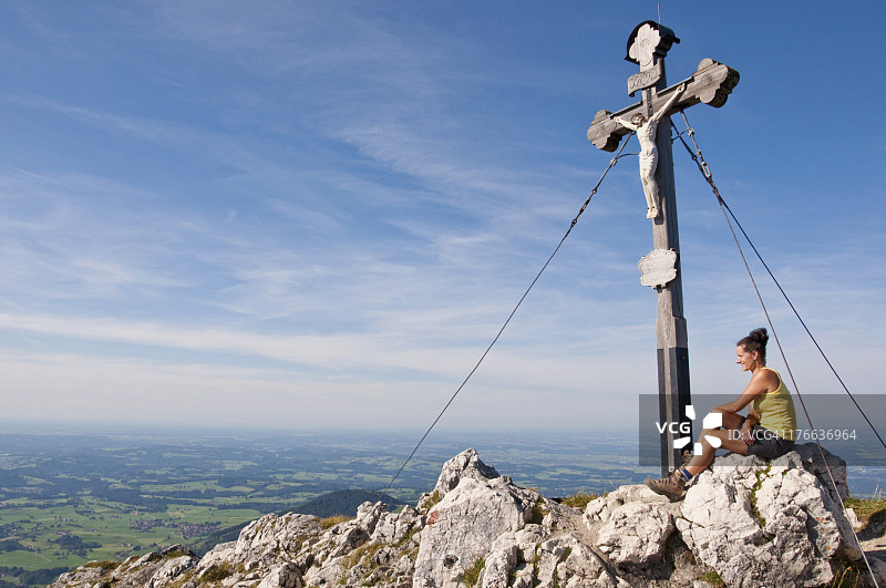 德国，巴伐利亚，中年成年女子坐在山顶上与十字架图片素材