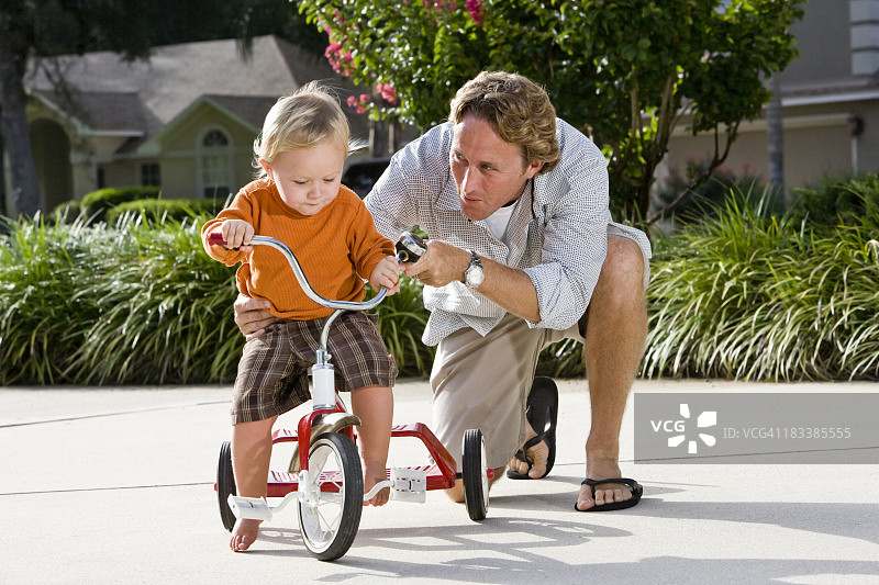 父亲帮助幼童骑三轮车图片素材