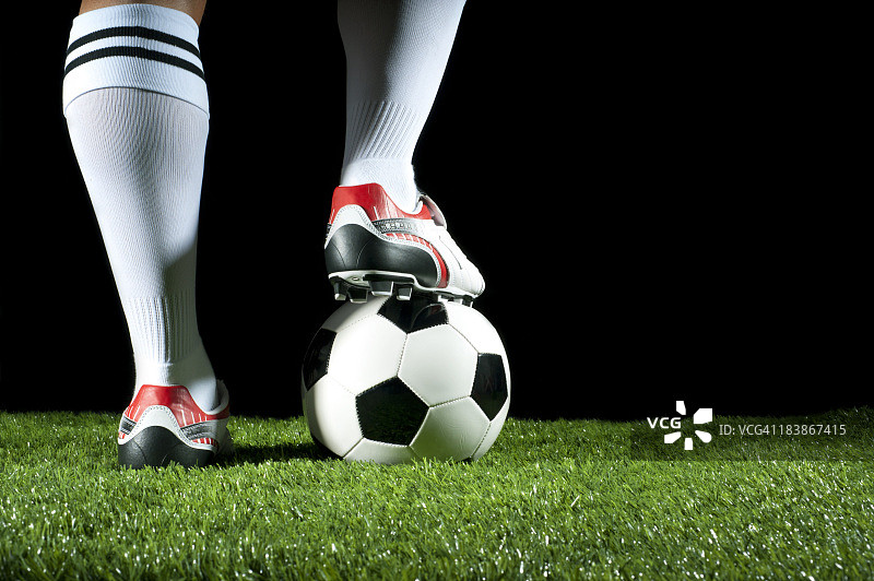 一只脚踩在足球上的人图片素材