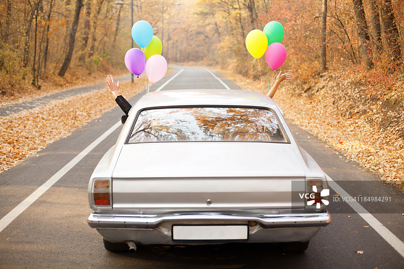 一对新婚夫妇把气球绑在他们的汽车上图片素材