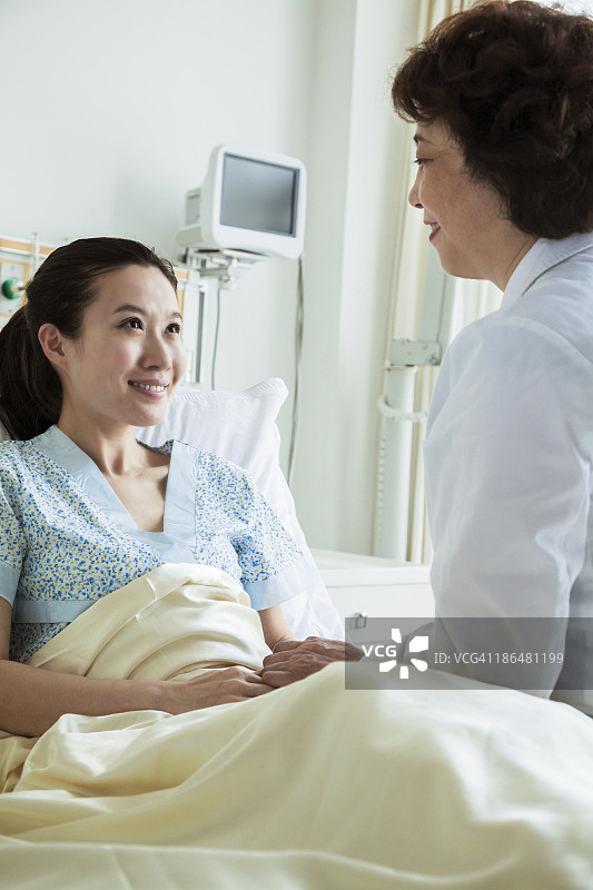 女医生坐在病床上与年轻的女病人讨论图片素材
