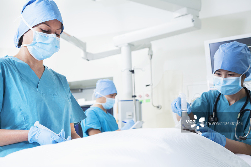 一组外科医生与躺在手术台上的病人一起工作图片素材
