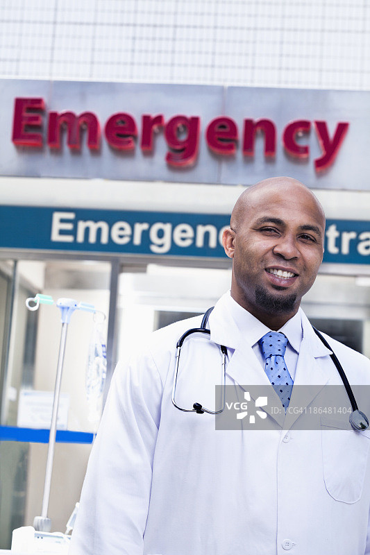 医院外微笑医生的肖像，背景是急诊室的标志图片素材