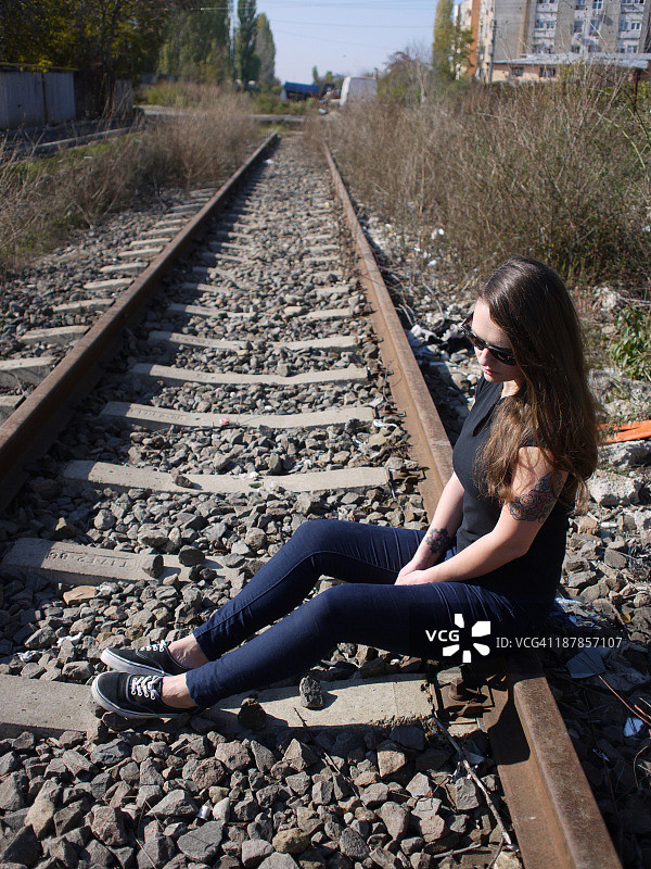 可悲的年轻女子坐在铁轨上图片素材
