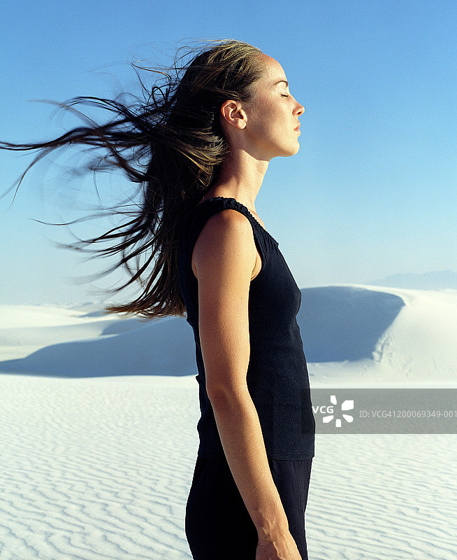 闭着眼睛的女人站在沙漠里，侧视图片素材