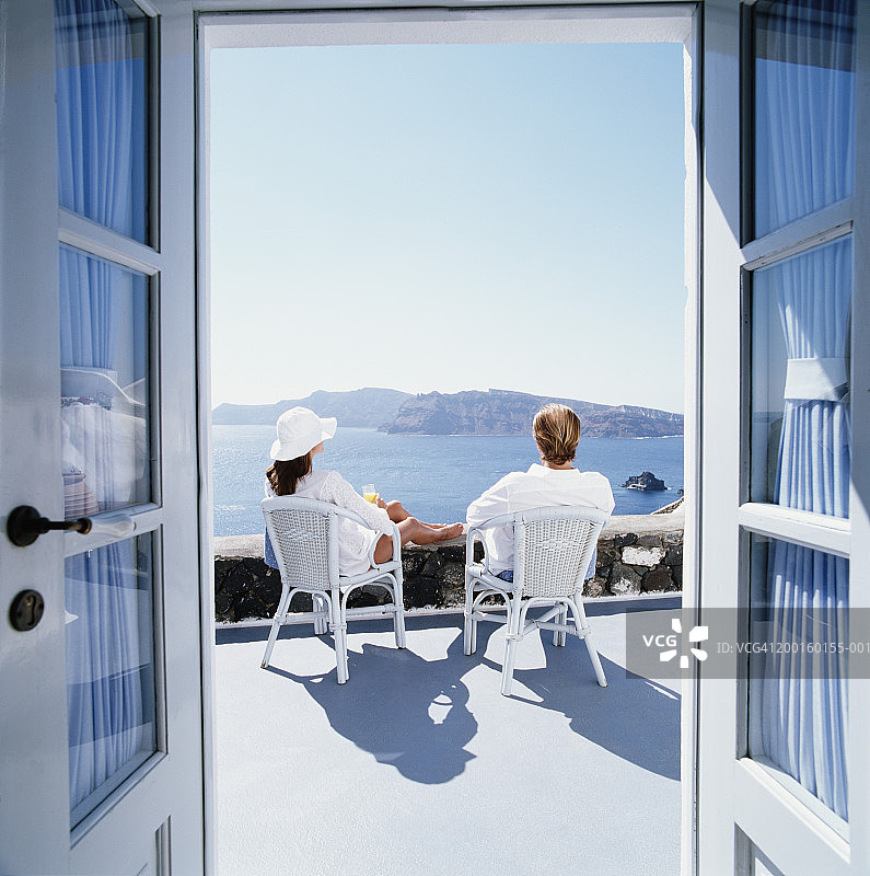 一对夫妇坐在阳台上俯瞰大海，透过门口可以看到大海图片素材