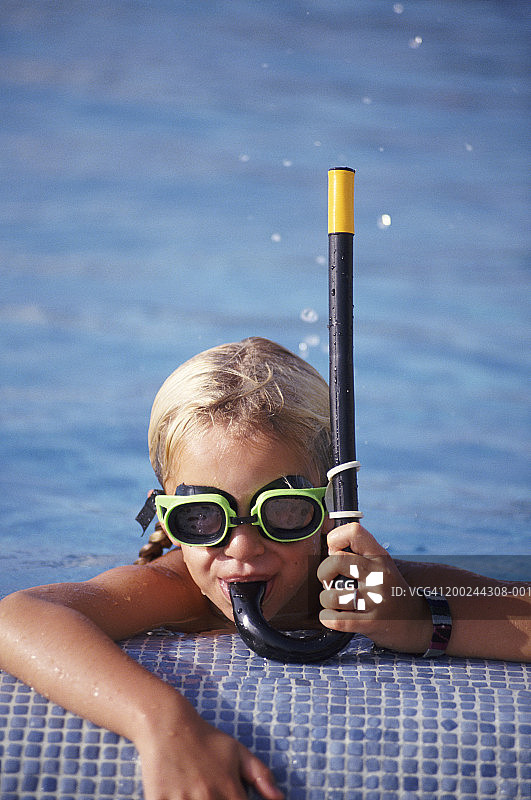 头和肩膀的女孩靠在游泳池的边缘，戴着通气管和护目镜，特写，肖像图片素材