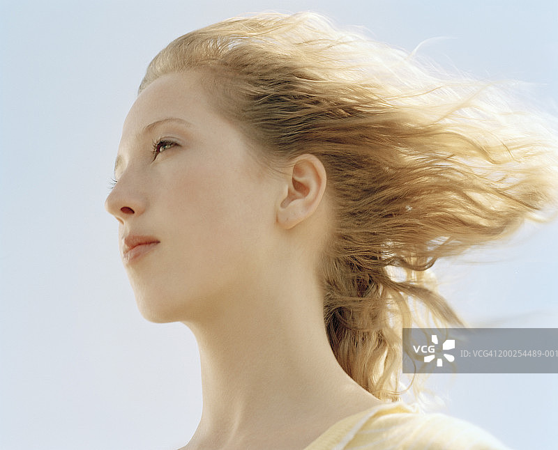 年轻女子的头发在风中吹拂，侧面，特写图片素材