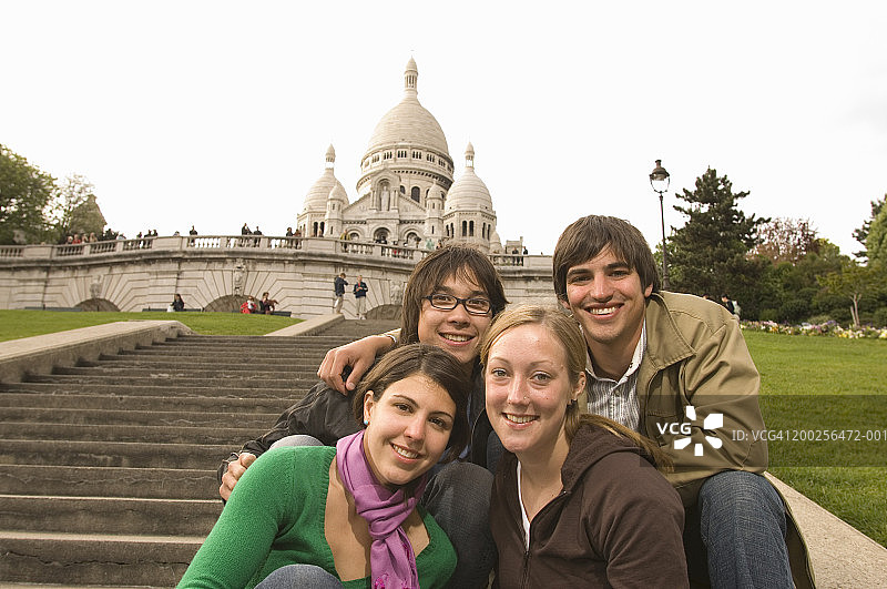 法国，巴黎，四个年轻人坐在圣心教堂旁边的楼梯上图片素材