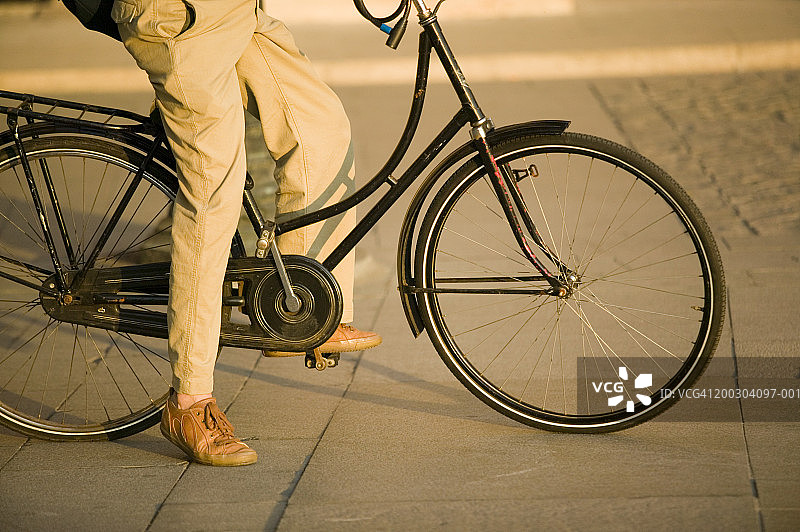 男子骑着自行车坐在人行道上，地势较低图片素材