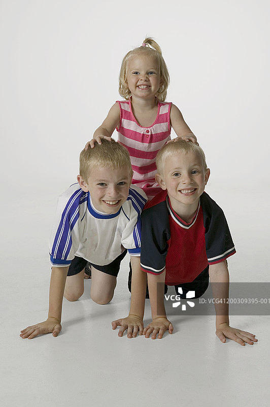 3个孩子(4-5岁)，组成人体金字塔，在工作室摆姿势，画像图片素材