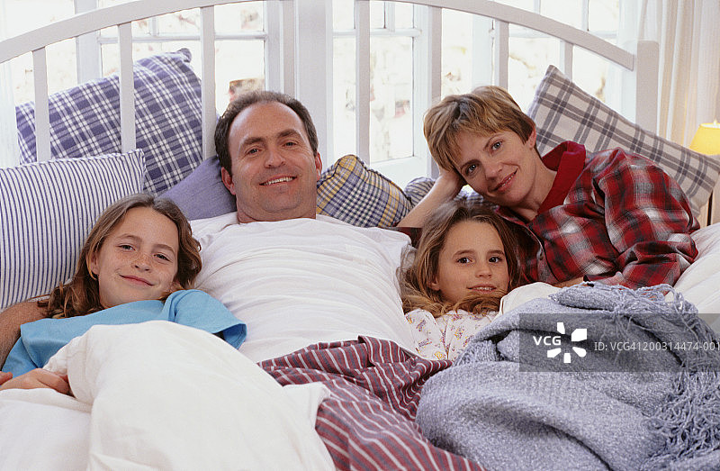 父母与两个女儿躺在床上(8-9)(10-11)，肖像图片素材