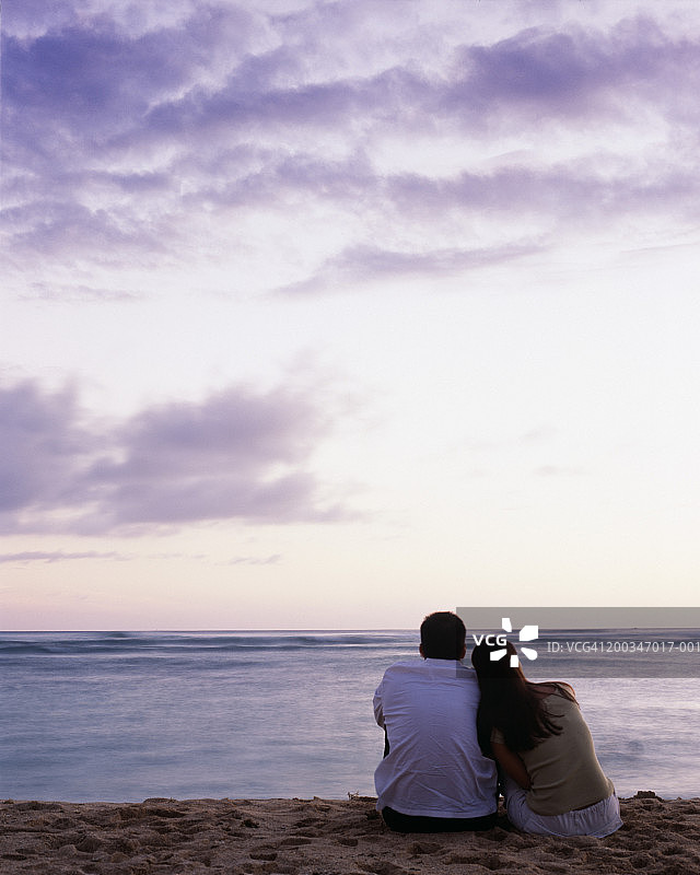 美国，夏威夷，瓦胡岛，男人和女人坐在海滩上日落，后视图图片素材