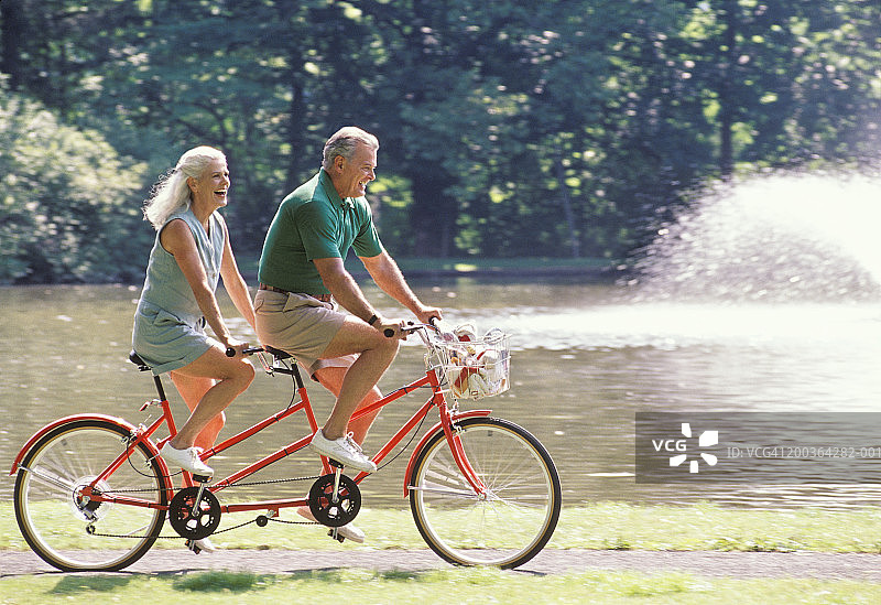 成熟夫妇骑双人自行车，侧视图片素材