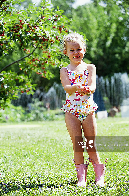 女孩(2-4人)穿着泳衣和粉色靴子，手拿樱桃，肖像图片素材