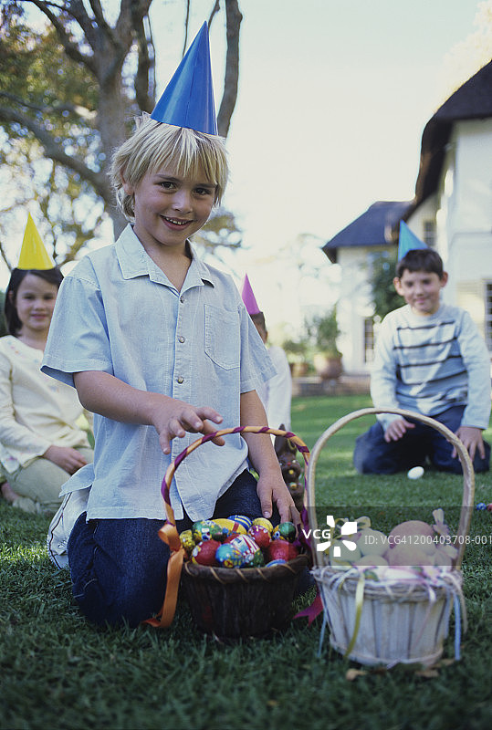 女孩和男孩(7-10)在花园里戴着派对帽和复活节彩蛋图片素材