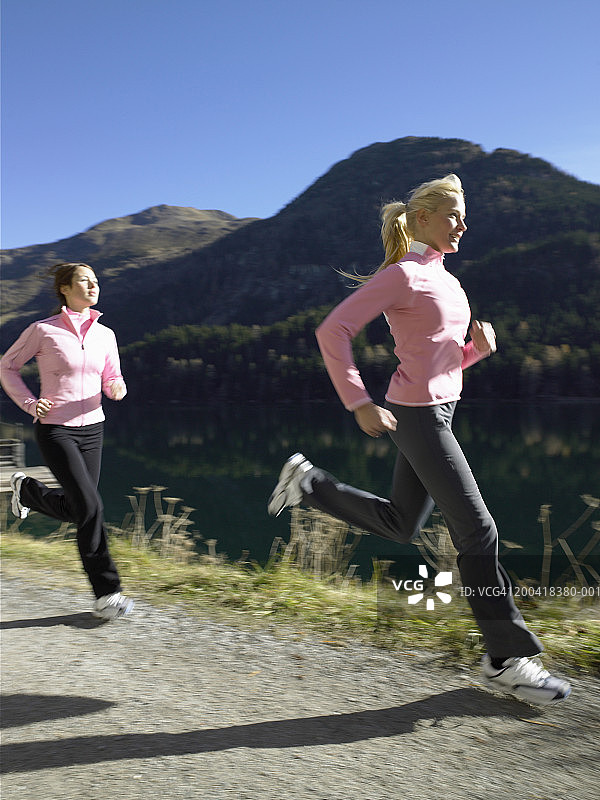 两个女人在湖边的小路上奔跑(模糊的运动)图片素材