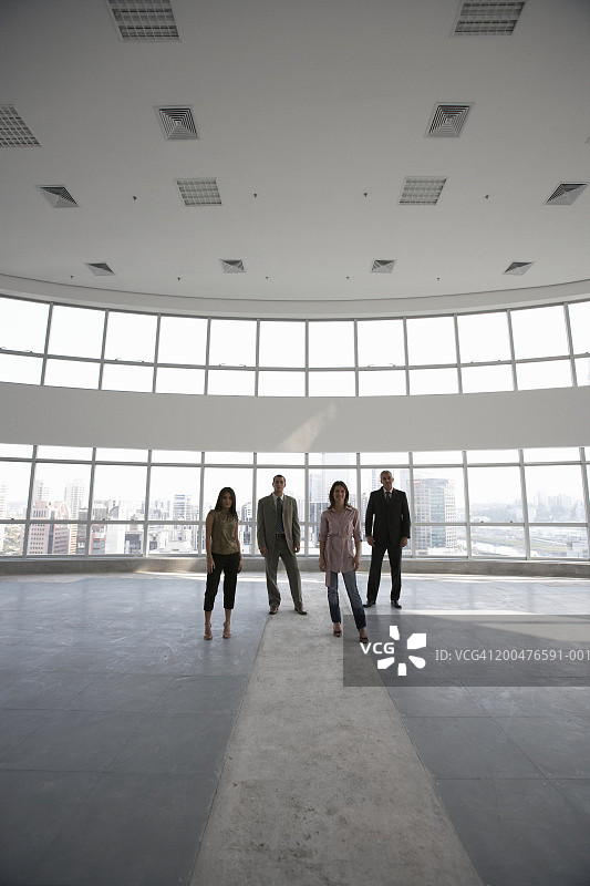 四名高管站在空荡荡的办公楼里，画像图片素材
