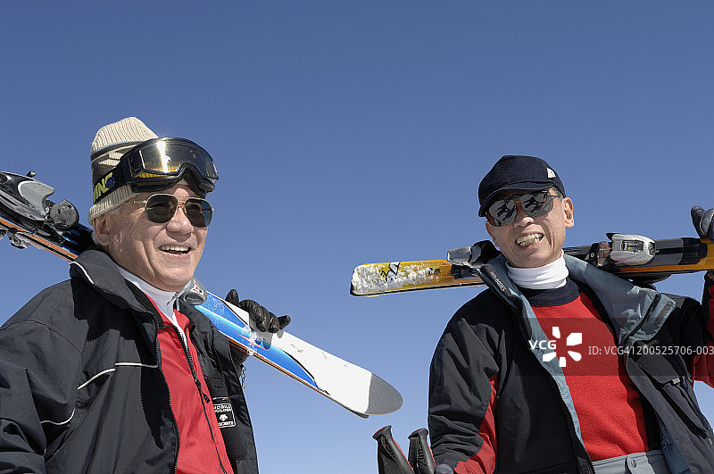 两个老人扛着滑雪板，面带微笑图片素材