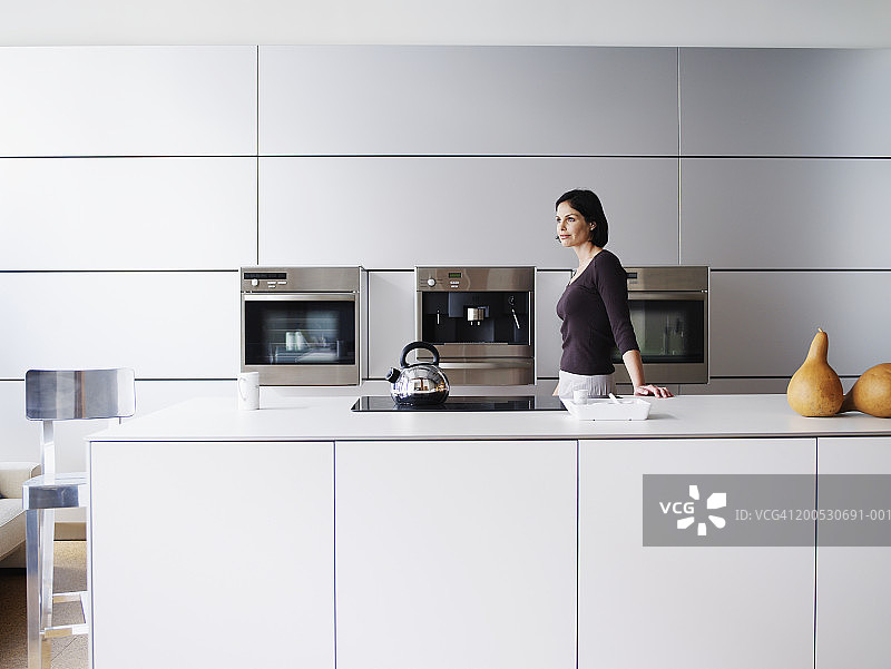 女人站在家庭厨房，侧视图图片素材