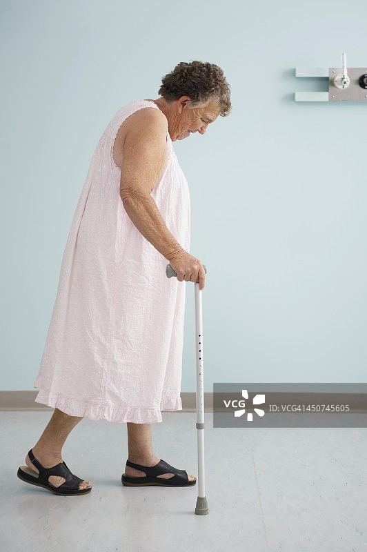 穿着睡衣拄着拐杖走路的老妇人图片素材