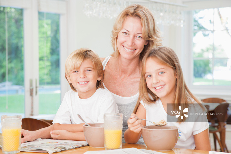 一个女人和两个小孩在厨房吃早餐图片素材