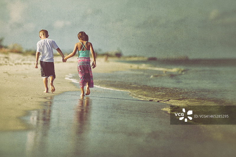 男孩和女孩手牵着手走在海滩上图片素材