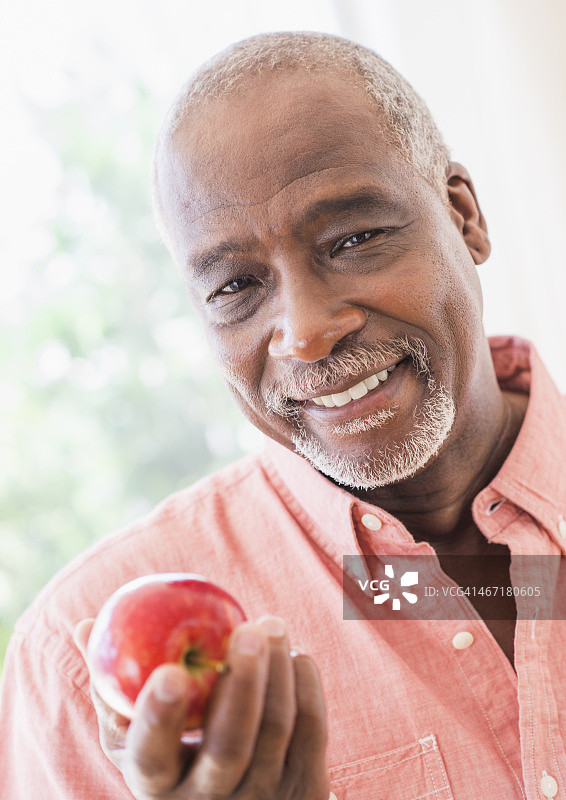 美国，新泽西州，泽西城，一个男人拿着红苹果的肖像图片素材