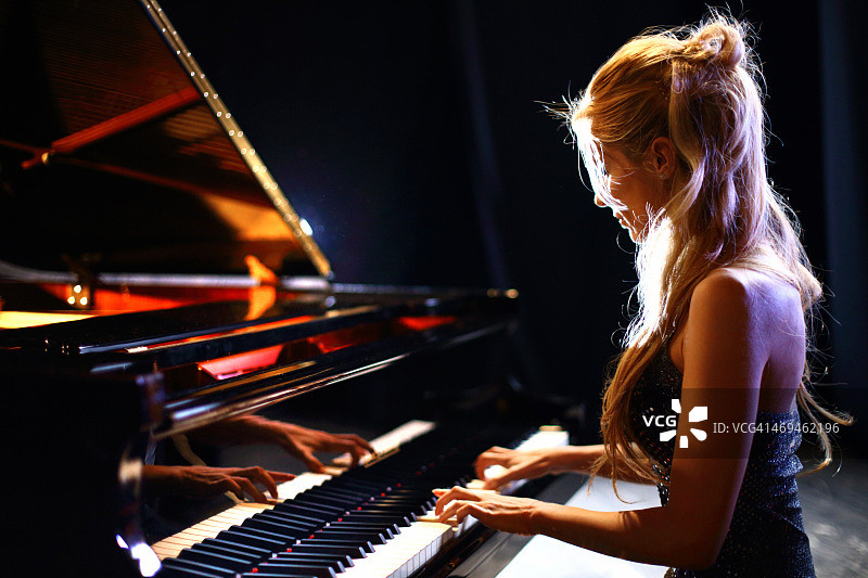 在音乐会上弹奏钢琴的女人。图片素材