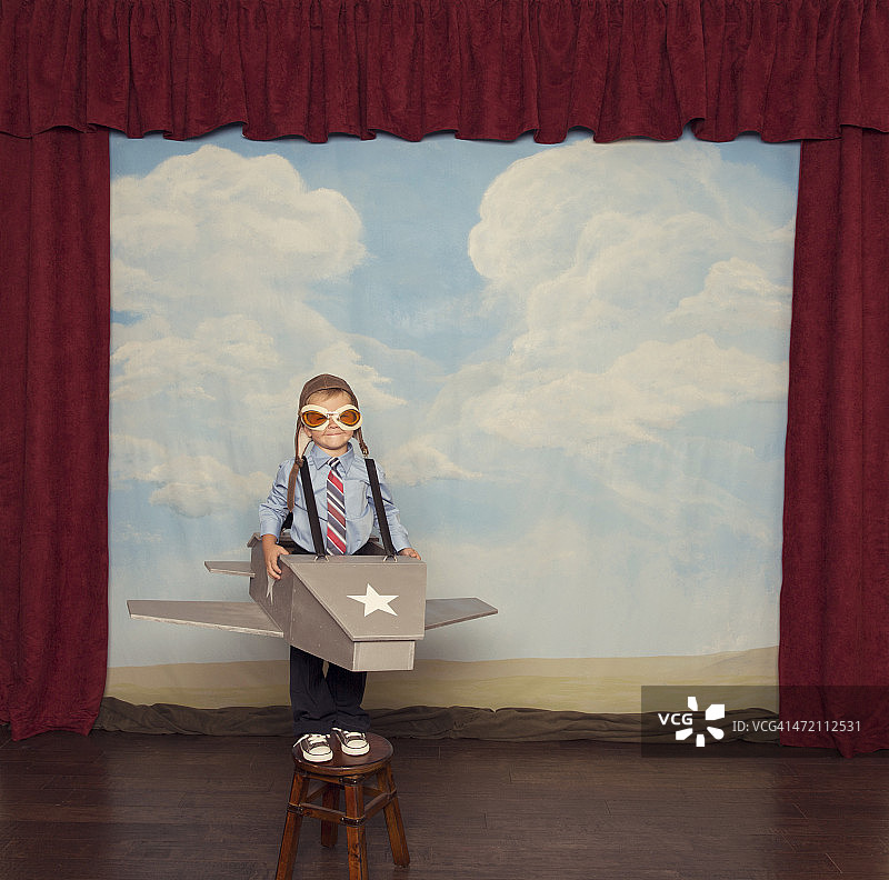 小男孩打扮成飞行员在玩具飞机图片素材