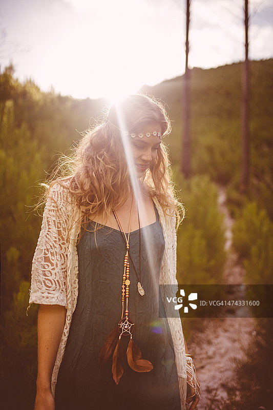 女孩穿着波西米亚服装在自然小径上与太阳耀斑图片素材