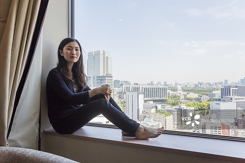 年轻的现代日本妇女坐着看风景图片素材