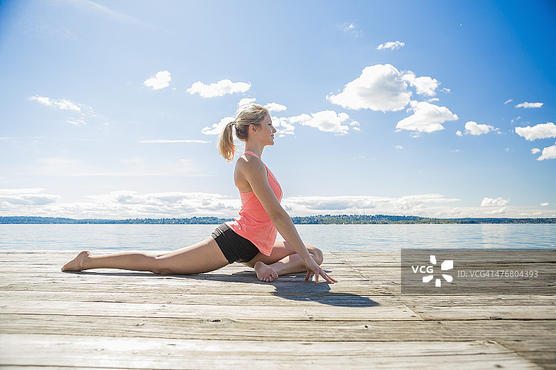 一个白人女人在木制码头上练习瑜伽图片素材
