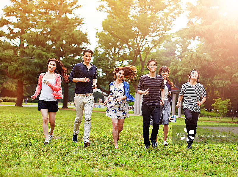 一群年轻的日本朋友在东京的公园里一起跑步。图片素材