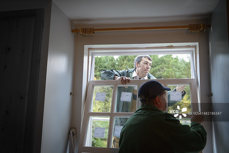 建筑工父子在房子里安装新窗户图片素材