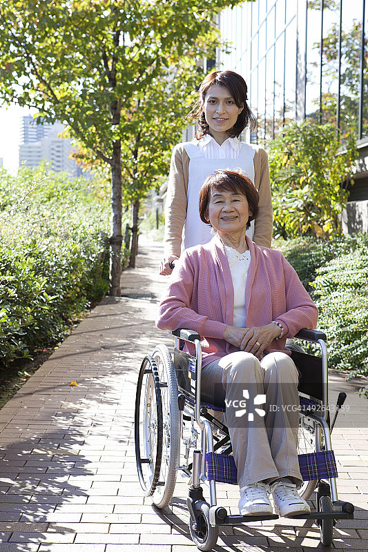 坐在轮椅上的老年妇女和街上的看护者图片素材