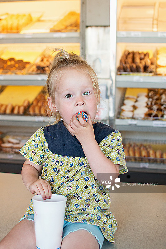 女孩吃着有糖屑的甜甜圈图片素材