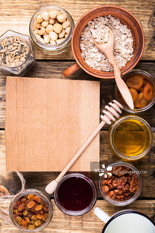 健康的早餐原料和有拷贝空间的木板。原始燕麦，干果，种子，蜂蜜，坚果和牛奶在乡村木板，俯视图图片素材