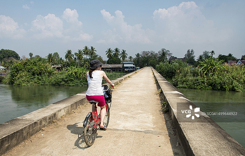 女游客在湄公河岸边骑车的后视图，Don Det，老挝图片素材