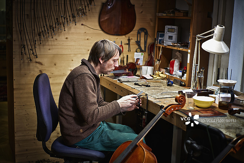 小提琴制造者在他的工作室锉大提琴机制图片素材