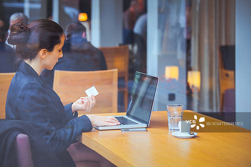 年轻的女商人在咖啡馆使用信用卡进行网上交易图片素材