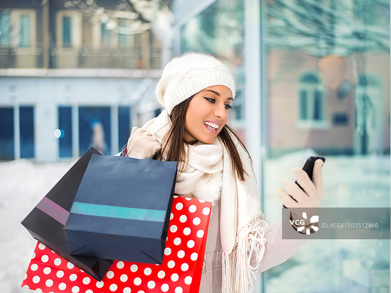 年轻女子在购物时使用手机图片素材