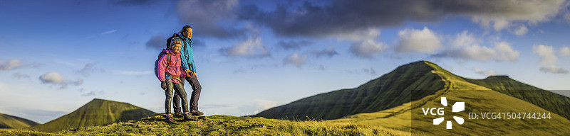 年轻的徒步旅行者在绿色的山脊上观看荒野日落全景图片素材