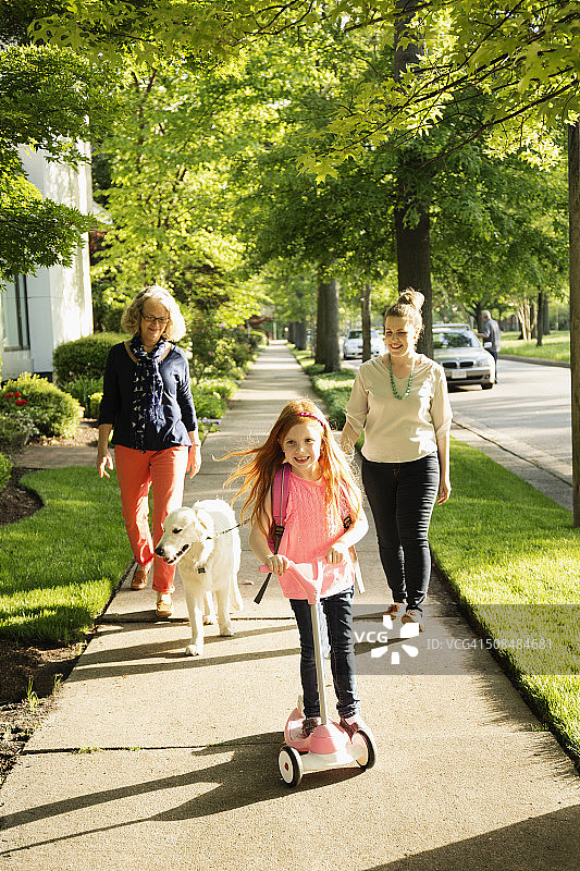 一个白人家庭在郊区的人行道上遛狗图片素材