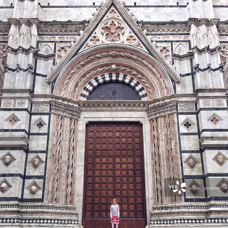 意大利，托斯卡纳，锡耶纳，女孩(12-13)站在大教堂前图片素材