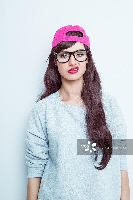 失望的年轻女子戴着书呆子眼镜和粉色棒球帽图片素材