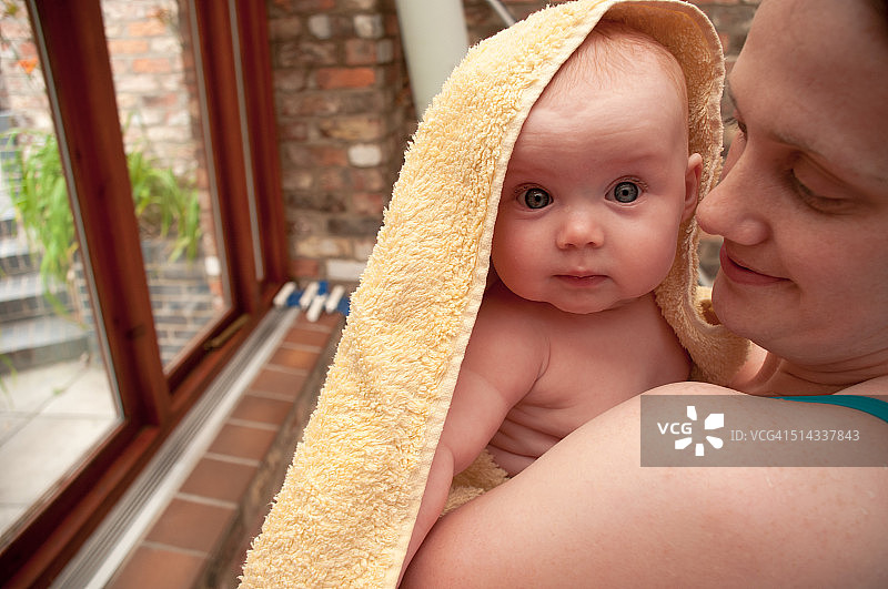 女婴裹着毛巾，由母亲抱着图片素材