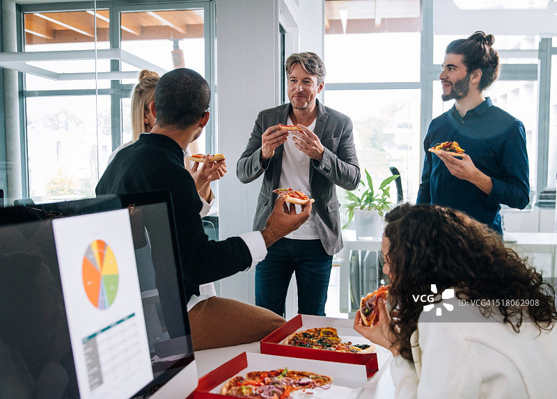 在小组会议上，员工一边讨论概念一边吃披萨图片素材