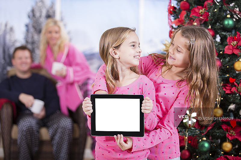 小女孩兴奋地打开数码平板电脑的圣诞礼物。空白屏幕。图片素材